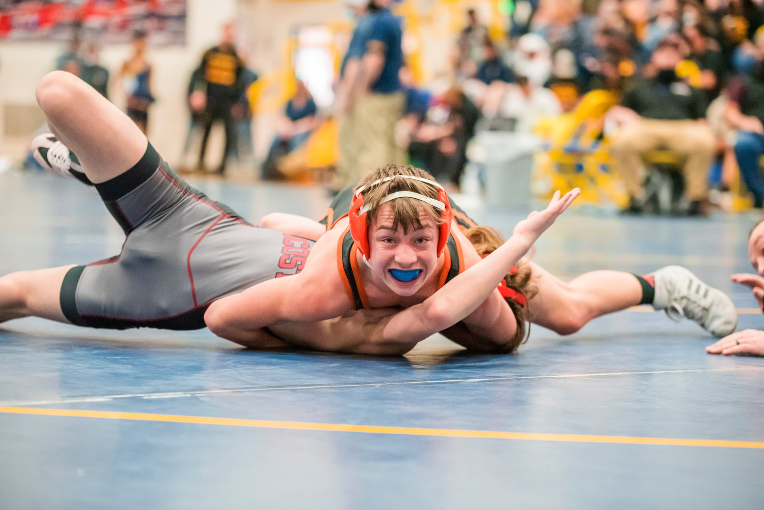 Rainier’s Conner Mounts looks to the camera as he pins his opponent during a wrestling match at Adna High School.
